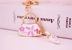 Detailed macro view of enamel handbag and high heel charms on a gold-tone keychain hook