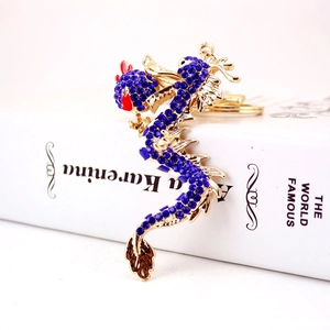 Portachiavi drago dorato con strass blu posizionato su un libro bianco decorativo