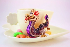 Detail of a Chinese dragon keychain featuring purple crystals on a coffee cup rim