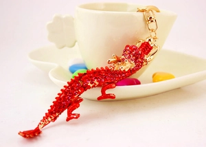 Détail d'un porte-clés dragon avec des strass rouges et une finition en métal doré