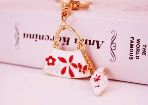 Detailed view of fashion keychain with white enamel handbag and high heel shoe charms