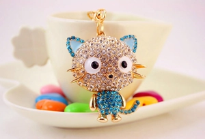 Close-up of golden cat keychain featuring white and blue crystals and sparkling rhinestones