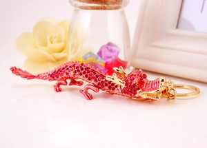 Détail d'un porte-clés dragon chinois doré orné de strass roses avec un anneau métallique
