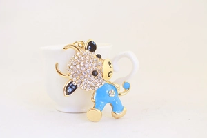 Detail of blue zodiac ox keychain with sparkling rhinestones on white ceramic cup