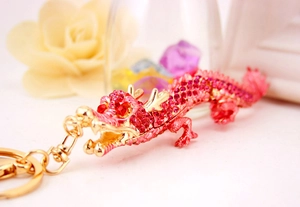 Vue macro d'un porte-clés dragon doré orné de cristaux rouges et roses sertis