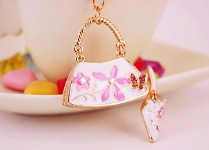 Macro detail of handbag keychain with pink petals and crystal butterfly charm