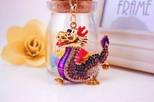 Detailed view of a golden dragon keychain with purple crystals and a spring clasp