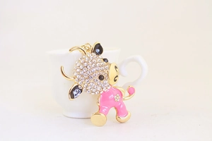Detail of pink enamel ox keychain with inlaid rhinestones leaning on a white cup