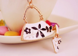 Detailed macro view of a gold handbag keychain with white enamel and a high heel charm
