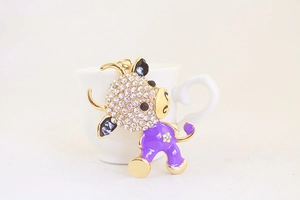 Detailed macro view of a cute cartoon ox keychain with purple enamel and white crystals