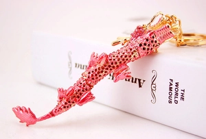 Vue détaillée du porte-clés dragon en métal rose avec des accents dorés et design ajouré