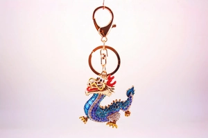 Detailed close-up of a golden Chinese dragon keychain with blue and white crystals