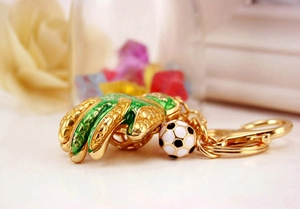 Detail of soccer glove keychain with green enamel and rhinestones next to a ball