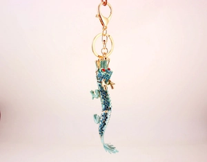 Détail du porte-clés dragon doré avec strass bleus étincelants et yeux rouges décorés