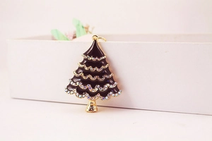 Close-up of a golden Christmas tree keychain with black enamel and colorful rhinestones