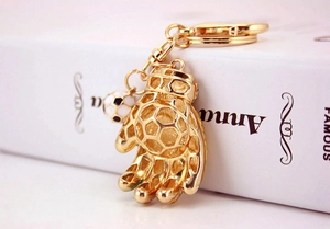 Detail of golden soccer goalkeeper glove and miniature ball charm on metal keychain