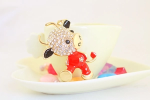 Close-up of a cartoon cow keychain with sparkling rhinestones on a beige cup edge
