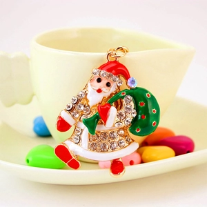 Enameled Santa Claus metal keychain with rhinestones hanging on a yellow ceramic cup