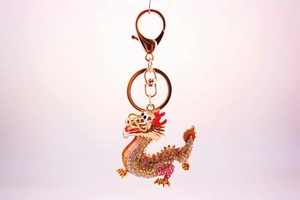 Close-up of golden zodiac dragon keychain with pink and silver crystal embellishments