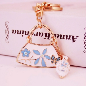 Creative handbag keychain with blue flower pattern, gold border, and sparkling rhinestones
