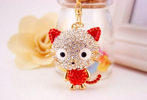 Close-up of a gold cat keychain with white and red crystals in a cozy setting
