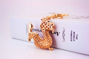 Detailed close-up of golden dragon keychain with hollow scales on a white book