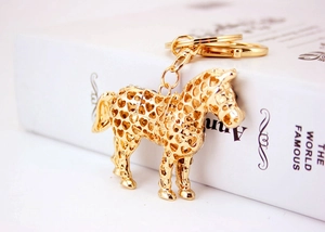 Detailed close-up of golden horse keychain with heart cut-outs and crystal accents
