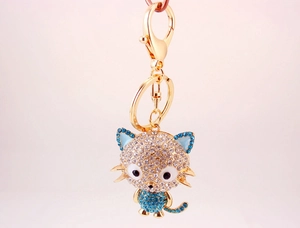 Detailed view of a golden cartoon cat keychain with white and blue rhinestones
