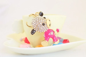 Close-up of cute cartoon calf keychain with pink enamel and sparkling white rhinestones