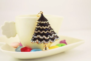 Close-up of black enamel Christmas tree keychain with sparkling crystals and gold plating