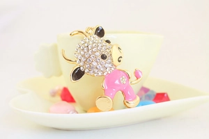 Detail of cute golden cow keychain with pink enamel, white rhinestones and floral back