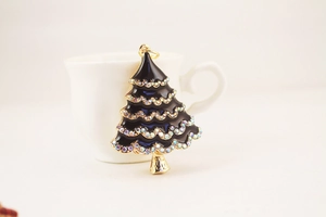 Close-up of a metal Christmas tree keychain with black enamel and colorful rhinestones