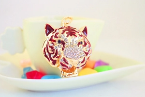 Détail macro d'un porte-clés tête de tigre plaqué or avec émail rouge et strass brillants