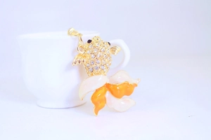 Detail showing crystal koi fish keychain with vibrant orange enamel tail and gold finish