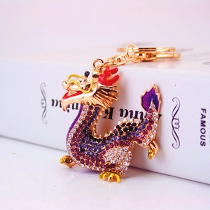 Exquisite golden dragon keychain with purple rhinestones on a white book prop