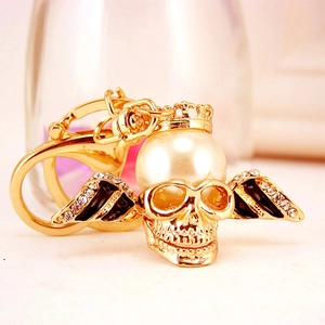 Golden skeleton keychain with crown, black wings and crystal pearl details