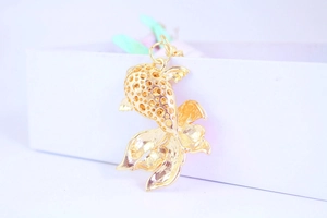 Macro detail of golden koi fish pendant with hollow honeycomb pattern and elegant tail design