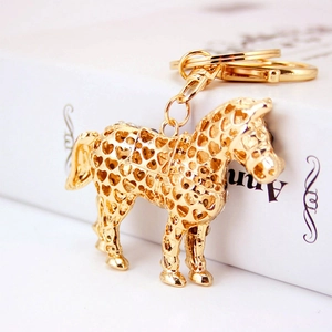 Golden horse keychain with heart cutout pattern and lobster clasp on book background