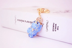 Detail of light blue Pixiu keychain with gold metal edges and white rhinestones decoration