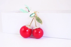 Close-up of sparkling rhinestone cherry charm with red spheres and gold leaf details