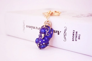 Detail of blue enamel Pixiu keychain with rhinestones against a classic book background