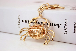 Detail of golden crab keychain featuring intricate hollow-out carving and lobster clasp