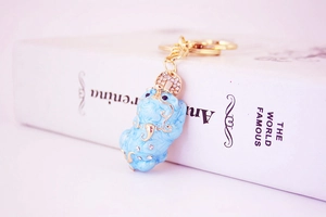 Close-up of a light blue Pi Xiu keychain with gold edges and sparkling rhinestones