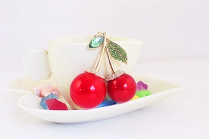 Close-up of sparkling cherry pendant with green rhinestones and red glossy finish
