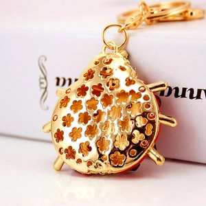 Cute golden ladybug keychain with floral cutout design and red enamel inlay for bags