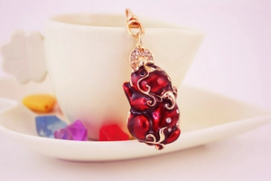 Detail of red rhinestone Pixiu charm with gold lobster clasp on a ceramic cup