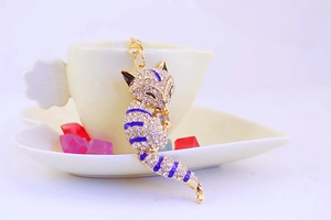 Close-up of crystal fox keychain with blue enamel stripes on a coffee cup background