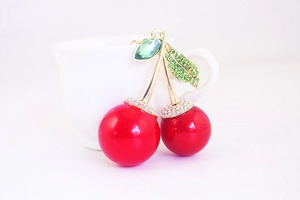 Close-up of a luxury red cherry keychain with gold stem and green sparkling leaf details