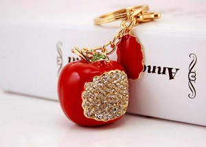 Macro detail of red apple keychain with sparkling crystals and golden metal ring