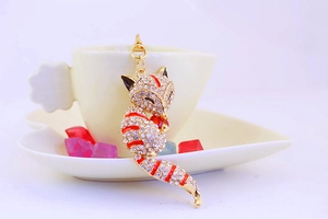 Detail of crystal fox keychain featuring red enamel tail and heart gem on ceramic cup